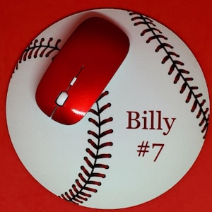 May include: A white baseball-themed mousepad with red stitching and a red mouse on top. The mousepad has the name "Billy" and the number "#7" printed on it.