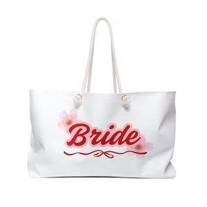 May include: White canvas tote bag with red text that says "Bride" and pink flowers on either side of the text.