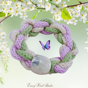 May include: A braided knit bracelet in pastel colors of lavender, green, and cream, with a large, round, marbled stone bead. A colorful butterfly hovers near the bracelet. The words "Easy Knit Studio" are at the bottom.