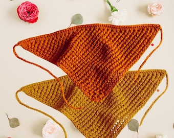 May include: Two handmade crochet bandanas in shades of orange and mustard yellow. The bandanas are triangular with a textured stitch pattern and long ties. The background includes flowers and the text "Easy Knit Studio".