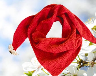 May include: A vibrant red triangular scarf with a textured weave. The scarf is draped, with one end adorned with a butterfly. The background features white flowers and a soft blue sky. The text "Easy Knit Studio" is in the upper left corner.