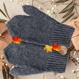 Puede incluir: Un par de guantes de punto grises con textura acanalada. Los guantes están hechos de un hilo suave y cálido y son perfectos para mantener las manos calientes en invierno.