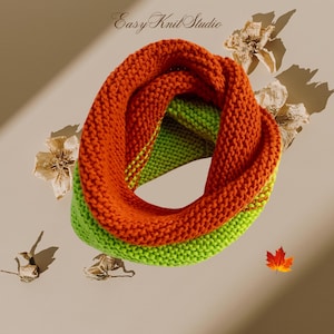 May include: A knitted infinity scarf in orange and green. The scarf is folded in half and the ends are tucked into the loop.