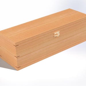 Può includere: Una scatola rettangolare in legno con finitura marrone chiaro. La scatola ha un coperchio incernierato e una piccola chiusura color oro. Gli angoli della scatola sono uniti con giunti a coda di rondine. La scatola è progettata per contenere una bottiglia.