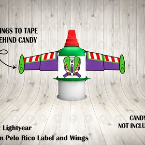 Op de afbeelding: Buzz Lightyear-thema party-gunst met een groen en paars label en vleugels. Het label heeft een cartoonafbeelding van Buzz Lightyear. De vleugels zijn met tape aan het label bevestigd. De tekst "WINGS TO TAPE BEHIND CANDY" staat op de afbeelding. De tekst "Buzz Lightyear Pelon Pelo Rico Label and Wings" staat onder de afbeelding. De tekst "CANDY NOT INCLUDED!" staat in de rechterbenedenhoek van de afbeelding.