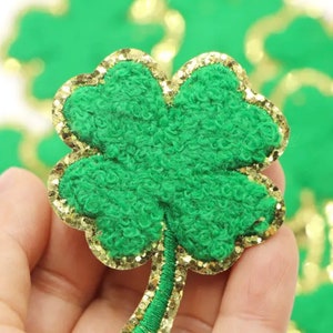 May include: Green felt shamrock with a gold glitter outline. The shamrock is a popular symbol of good luck and is often used for St. Patrick's Day decorations.