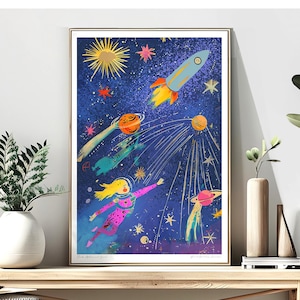 May include: A framed art print featuring a whimsical space scene. A blonde astronaut in a pink spacesuit floats among planets, rockets, and stars against a dark blue background. The print includes the text "Pink Astronaut Girl".