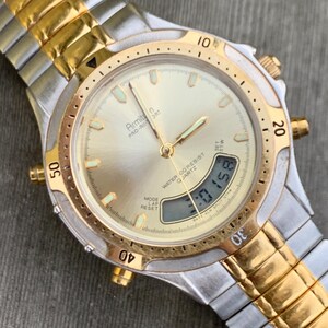 May include: A gold and silver two-tone Armitron Pro-Air-Ort watch with a white face and a digital display. The watch has a gold band and a water resistant feature.