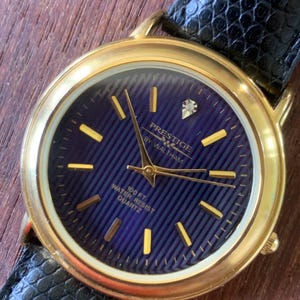 Prestige by Waltham Diamond Dial Quartz Watch.  Gold Tone with striped dial, black and deep blue. Classic Retro Style. Leather Band. Unworn.