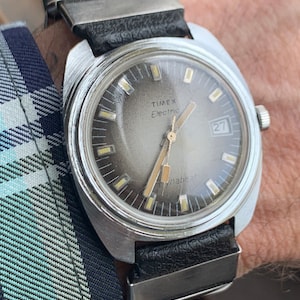 1970s Timex Dynabeat Electric Watch, Large Chrome Case w/Sunburst Dial & Date. In Good Overall Condition with Cool 1970s Metal Stripe Strap