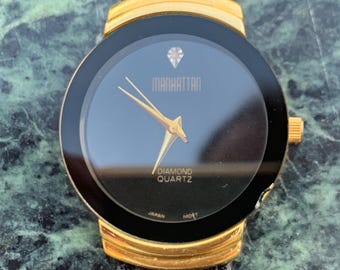 Manhattan 'Diamond' Quartz Museum watch. Fancy lugs, great gold tone. Black dial without indices. Keeps time well. 1990s. Small chip crystal