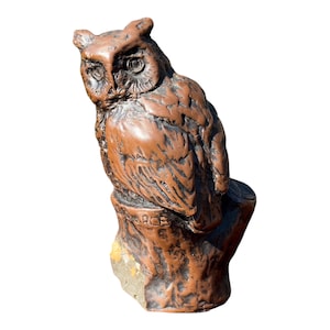 Puede incluir: Una figura de búho de cerámica marrón posada sobre una base de tronco de árbol texturizado. El búho tiene plumas detalladas y ojos grandes. La palabra PIERCE está grabada en la parte frontal del tronco. La escultura tiene un acabado brillante.