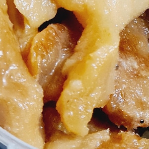 May include: Close-up of a container filled with light brown, translucent, and slightly sticky food. The food appears to be a type of preserved fruit or candy.