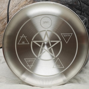 May include: A silver metal plate with a pentagram and the words "Spirit", "Air", "Water", "Earth", and "Fire" engraved around it.