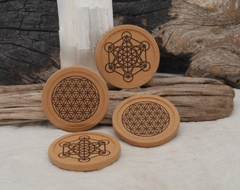 Könnte beinhalten: Vier runde Untersetzer aus Kork mit geometrischen Mustern. Zwei Untersetzer zeigen das Muster der Blume des Lebens, und die anderen beiden zeigen den Metatron-Würfel. Die Untersetzer sind hellbraun mit dunkelbraunen geätzten Designs.
