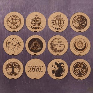 May include: A collection of twelve round, light brown coasters with various mystical and witchy designs. The designs include a pentagram, text that reads "Fueled by Crystals & Coffee", a tree of life, and a witch silhouette.