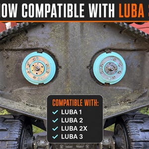 Op de afbeelding: De onderkant van een robotmaaier-dek met twee lichtblauwe ronde mesbevestigingshubs, oranje zijframes en zwarte wielen met profiel. De tekst bovenaan luidt NOW COMPATIBLE WITH LUBA 3, en een centraal vak vermeldt COMPATIBLE WITH: LUBA 1, 2, 2X, 3.