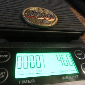 K&ouml;nnte beinhalten: Eine Gedenkm&uuml;nze mit roten, wei&szlig;en und blauen Akzenten, die mit "250 CELEBRATING FREEDOM & UNITY" gekennzeichnet ist, liegt auf einer Digitalwaage. Die Waage zeigt ein Gewicht von 46,0 Gramm an. Die Waage hat eine Timer-Funktion.