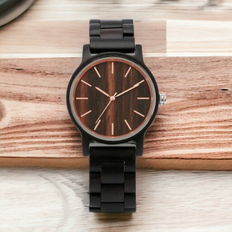 Men wristwatch crafted from Red Wood, Maple, and Ebony, featuring a full wooden case and bangle. Includes a quartz movement and folding clasp for secure wear. Eco-friendly and stylish timepiece for men.