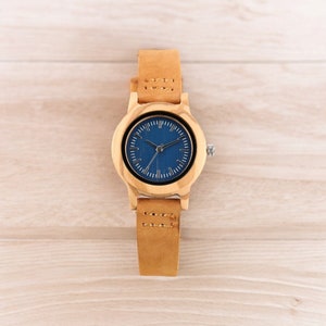 Stylish minimalist women watch featuring a vibrant blue dial, encased in natural bamboo wood. Slim genuine leather wristband complements this elegant timepiece, perfect for fashion-forward ladies.