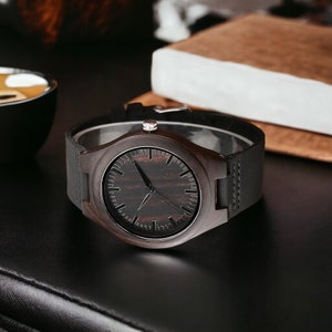 Classic ebony wood quartz men watch with a minimalist scale, round dial, and black genuine leather strap. Fashionable and casual accessory for men.
