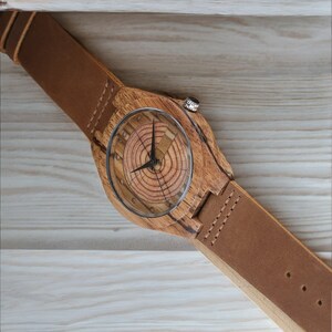 Men quartz wristwatch with a unique wooden design, showcasing annual rings and block points on the face, paired with black hands. Features a brown genuine leather strap and is ideal for sports and casual wear.