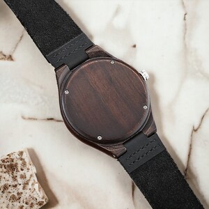 Classic ebony wood quartz men watch with a minimalist scale, round dial, and black genuine leather strap. Fashionable and casual accessory for men.