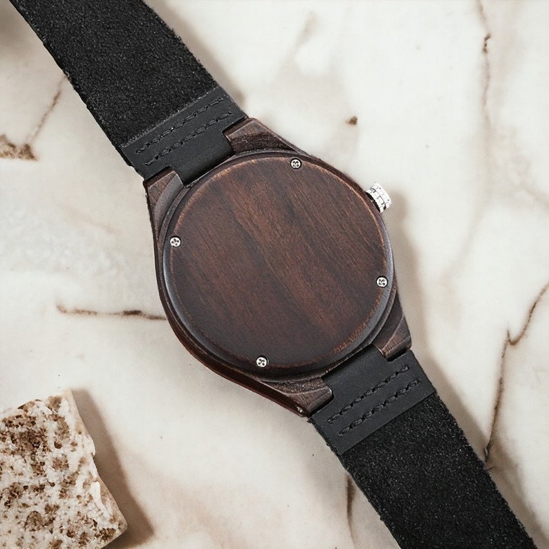 Classic ebony wood quartz men watch with a minimalist scale, round dial, and black genuine leather strap. Fashionable and casual accessory for men.