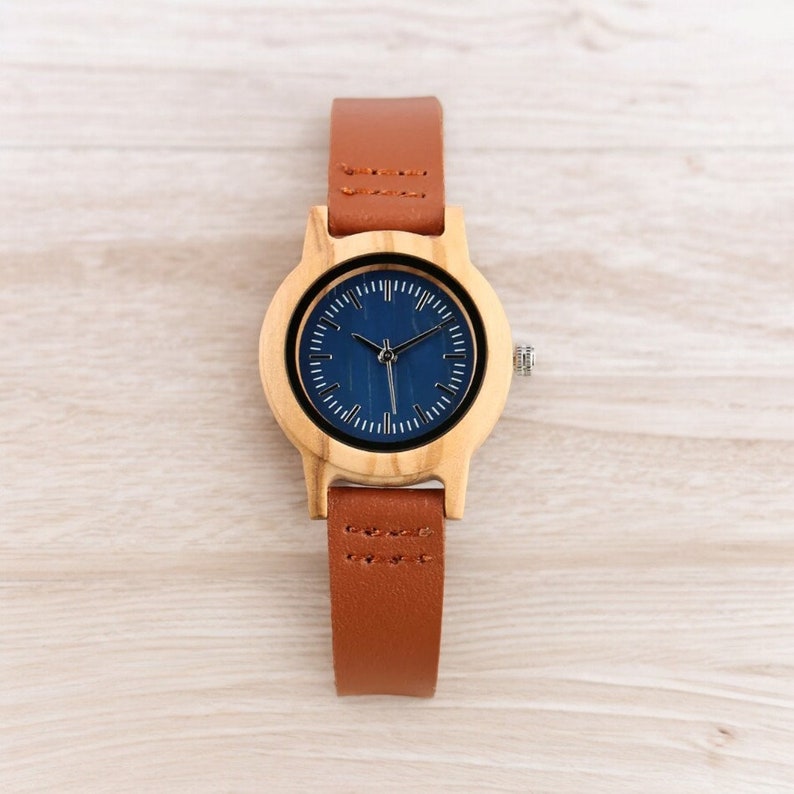Stylish minimalist women watch featuring a vibrant blue dial, encased in natural bamboo wood. Slim genuine leather wristband complements this elegant timepiece, perfect for fashion-forward ladies.
