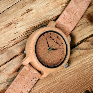 Pair of elegant wooden wristwatches with cork straps, presented in a luxury box. The bamboo watch face features a custom logo, making it a unique gift for couples. Handcrafted with attention to detail.