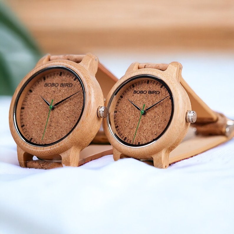 Pair of elegant wooden wristwatches with cork straps, presented in a luxury box. The bamboo watch face features a custom logo, making it a unique gift for couples. Handcrafted with attention to detail.