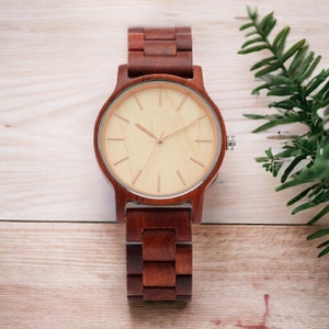 Men wristwatch crafted from Red Wood, Maple, and Ebony, featuring a full wooden case and bangle. Includes a quartz movement and folding clasp for secure wear. Eco-friendly and stylish timepiece for men.