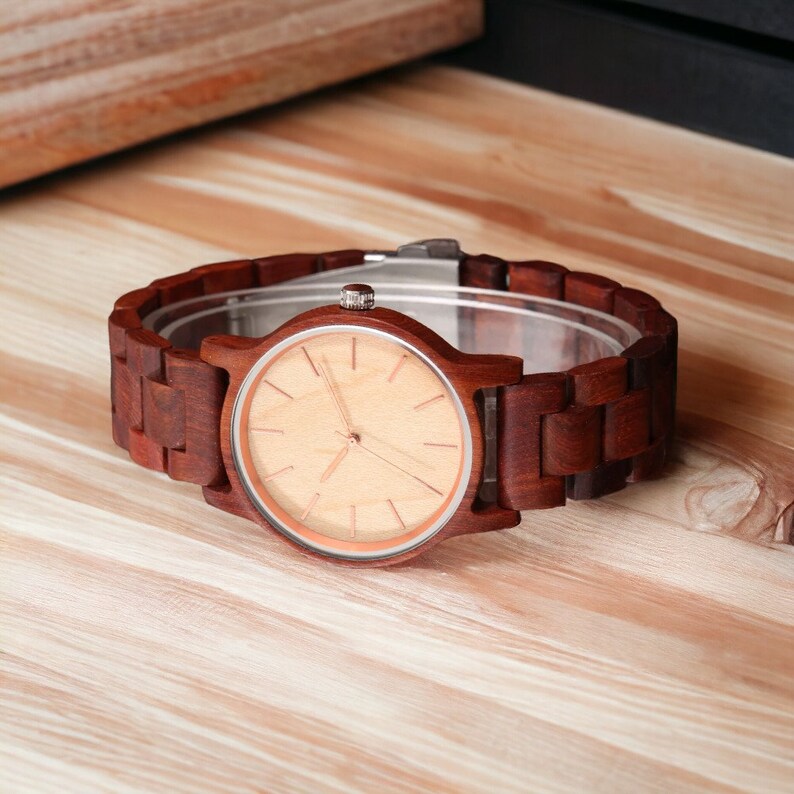 Men wristwatch crafted from Red Wood, Maple, and Ebony, featuring a full wooden case and bangle. Includes a quartz movement and folding clasp for secure wear. Eco-friendly and stylish timepiece for men.