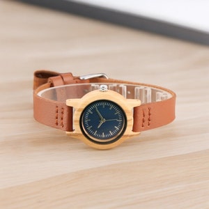 Stylish minimalist women watch featuring a vibrant blue dial, encased in natural bamboo wood. Slim genuine leather wristband complements this elegant timepiece, perfect for fashion-forward ladies.