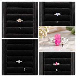 May include: Five wire-wrapped rings featuring various gemstones. Ring 1 has a tan stone, ring 2 a white stone, ring 3 a blue-tinted stone, ring 4 a large vibrant pink raw crystal, and ring 5 a small pink stone. All rings use silver-toned wire.