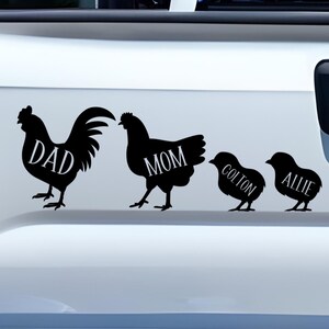 May include: A black vinyl decal applied to the white tailgate of a pickup truck. The design features silhouettes of a rooster labeled DAD, a hen labeled MOM, and two chicks labeled COLTON and ALLIE, arranged in a horizontal row from largest to smallest.
