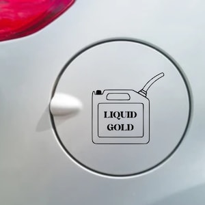 May include: A black and white decal of a gas can with the words "LIQUID GOLD" printed on it. The decal is on a silver car surface.