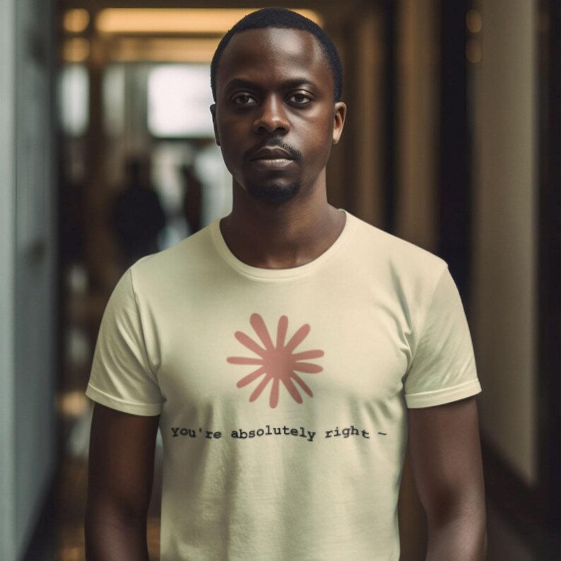 May include: A light beige t-shirt with a pink floral design and the text "You're absolutely right -" in black. The shirt is short-sleeved and worn by a person.