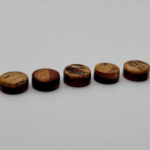 Puede incluir: Cinco clavijas de afinación de guitarra de madera con un patrón de veta de madera marrón y rojo.