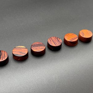 May include: Six round wooden knobs with a red and black wood grain pattern.