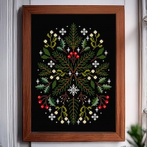 Può includere: Opera d'arte a punto croce in una cornice di legno. Il design presenta una disposizione simmetrica di foglie verdi, bacche rosse e accenti bianchi a forma di stella su sfondo nero. La cornice è di colore marrone caldo.