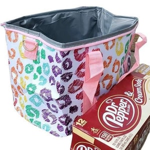 May include: A colorful tote bag with a rainbow leopard print design, pink handles, and a gray interior. Next to the bag is a 12-pack of Dr. Pepper & Cream Soda.
