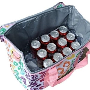 May include: A colorful insulated tote bag with a leopard print design, filled with cans of Dr. Pepper. The bag has pink handles and a silver interior, perfect for keeping drinks cold. The bag is designed to carry multiple cans.