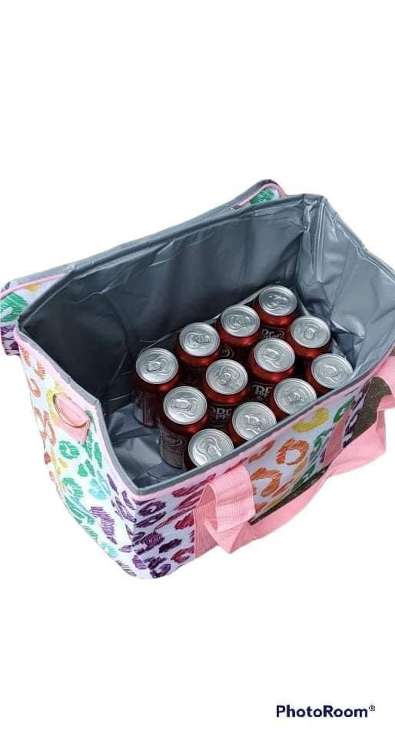 May include: A colorful insulated tote bag with a leopard print design, filled with cans of Dr. Pepper. The bag has pink handles and a silver interior, perfect for keeping drinks cold. The bag is designed to carry multiple cans.