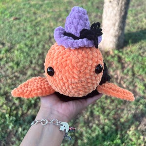May include: A crocheted orange and black octopus wearing a purple and black witch hat.