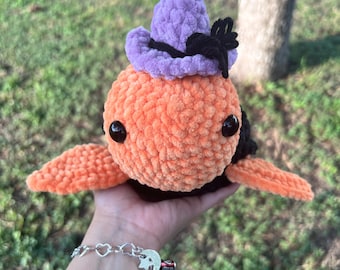 May include: A crocheted orange and black octopus wearing a purple and black witch hat.