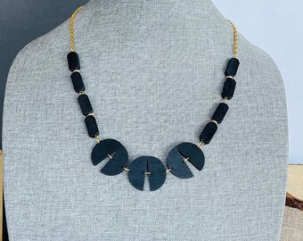 Colar statement em madeira preta, estilo geométrico boho-hippie, com corrente dourada.