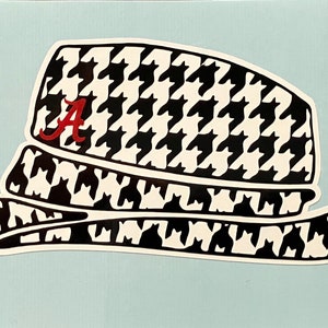 May include: A sticker of a fedora hat with a black and white houndstooth pattern. The hat has a red letter "A" on the front. The hat is set against a light blue background.