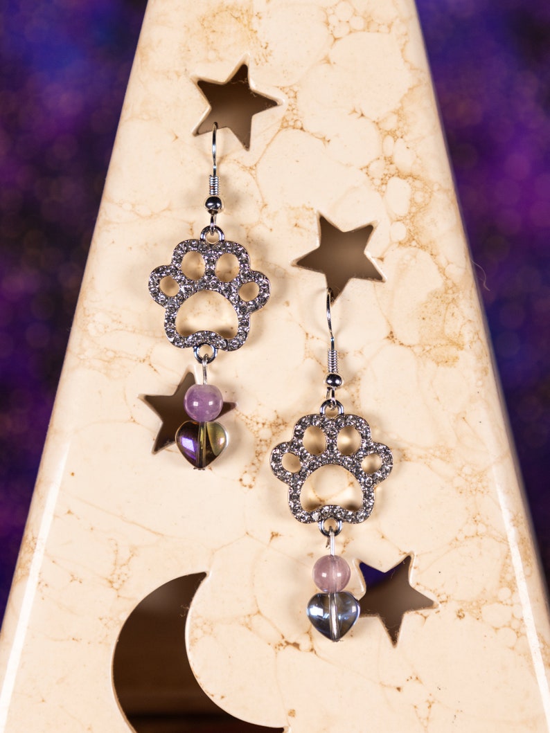 Shiny paw print earrings accented with rhinestones and purple beads.