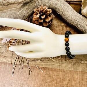 May include: A black beaded bracelet with a single tiger's eye bead.